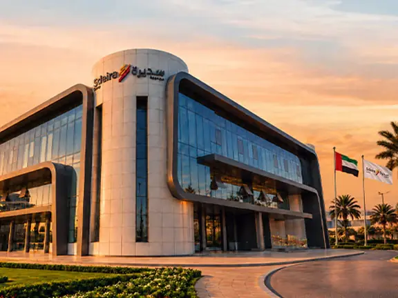 مبنى المقر الرئيسي لمجموعة سديرة عند الغروب وإلى جانبه علم الإمارات